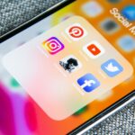 Social media app icons on a smartphone screen with a textured grey background